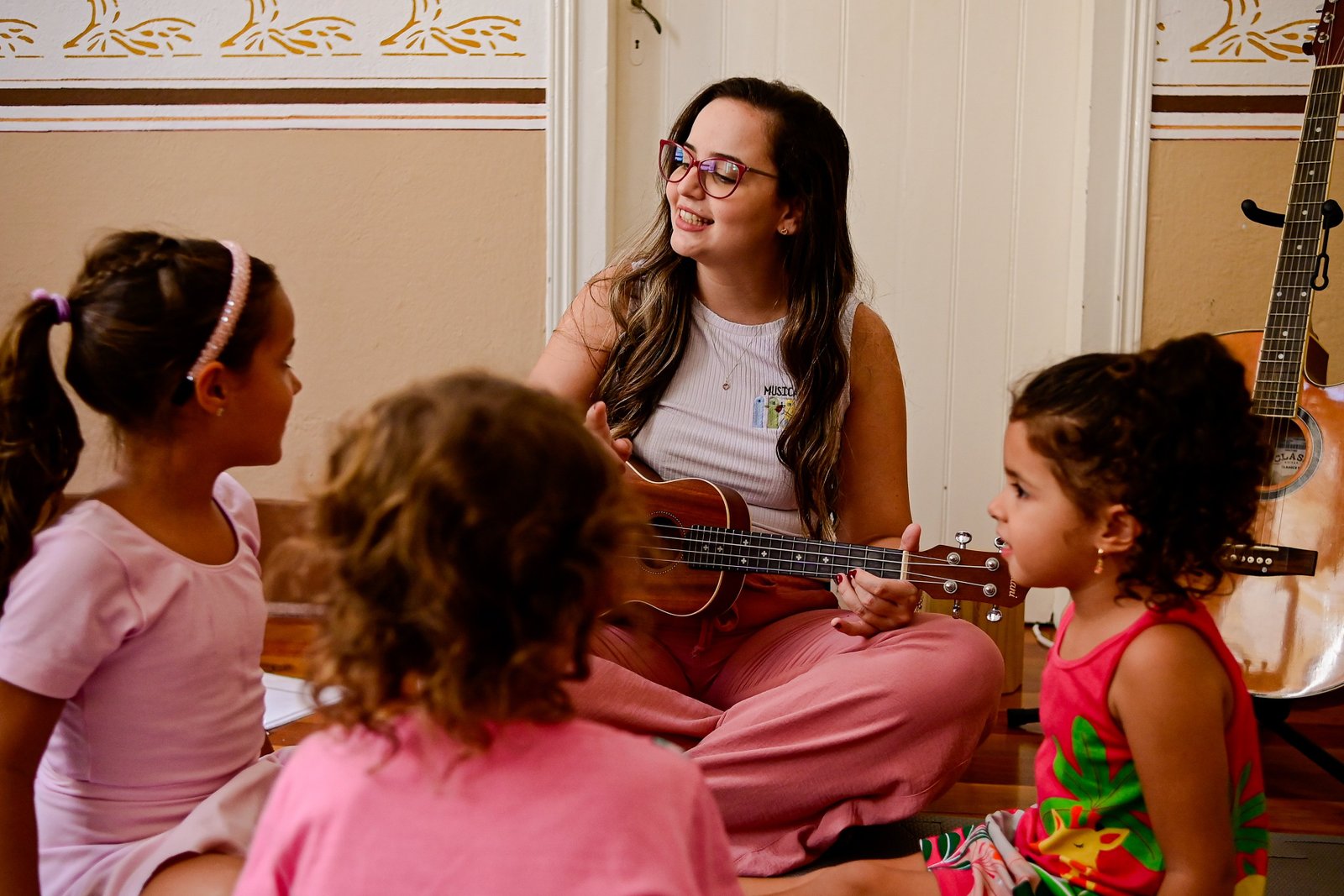 Isa Oliveira dando aula de musicalização com ukulele para crianças